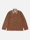 The Brown Meco Denim OG Bakers Jacket is shown laid flat against a solid white background. The jacket features a loose fit, a full button-through front, and a classic pointed collar. Three prominent patch pockets with angled corners are visible on the front, including one chest pocket and two lower pockets, all featuring contrast stitching.