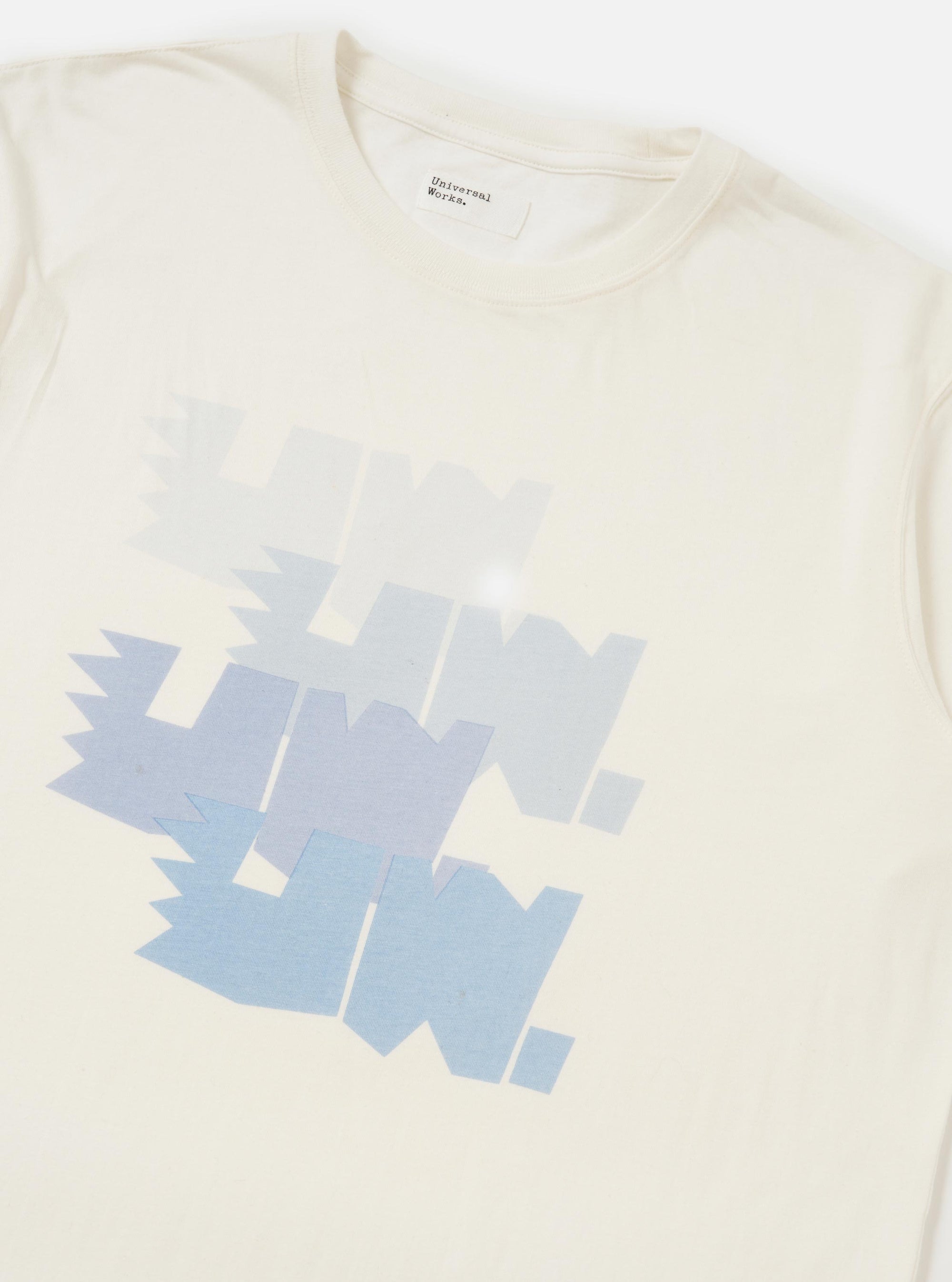 The Ecru Single Jersey Multi UW Print Multi UW Print Tee is displayed from a rear perspective, laid flat against a solid white background. The image highlights the short-sleeve construction, a simple crew neck, and a small woven branded label positioned near the straight hem.