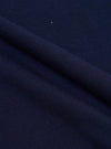 A close-up fabric swatch of the Navy Single Jersey Multi UW Print Multi UW Print Tee shows a detailed view of the navy blue cotton material. The image highlights the single jersey knit texture and the repeating multi-colored UW logo print across the surface.