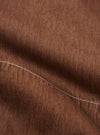 A detailed, close-up fabric swatch of the brown Meco denim used for the Marine Gilet. The image highlights the textured diagonal twill weave and the earthy brown color of the fabric.