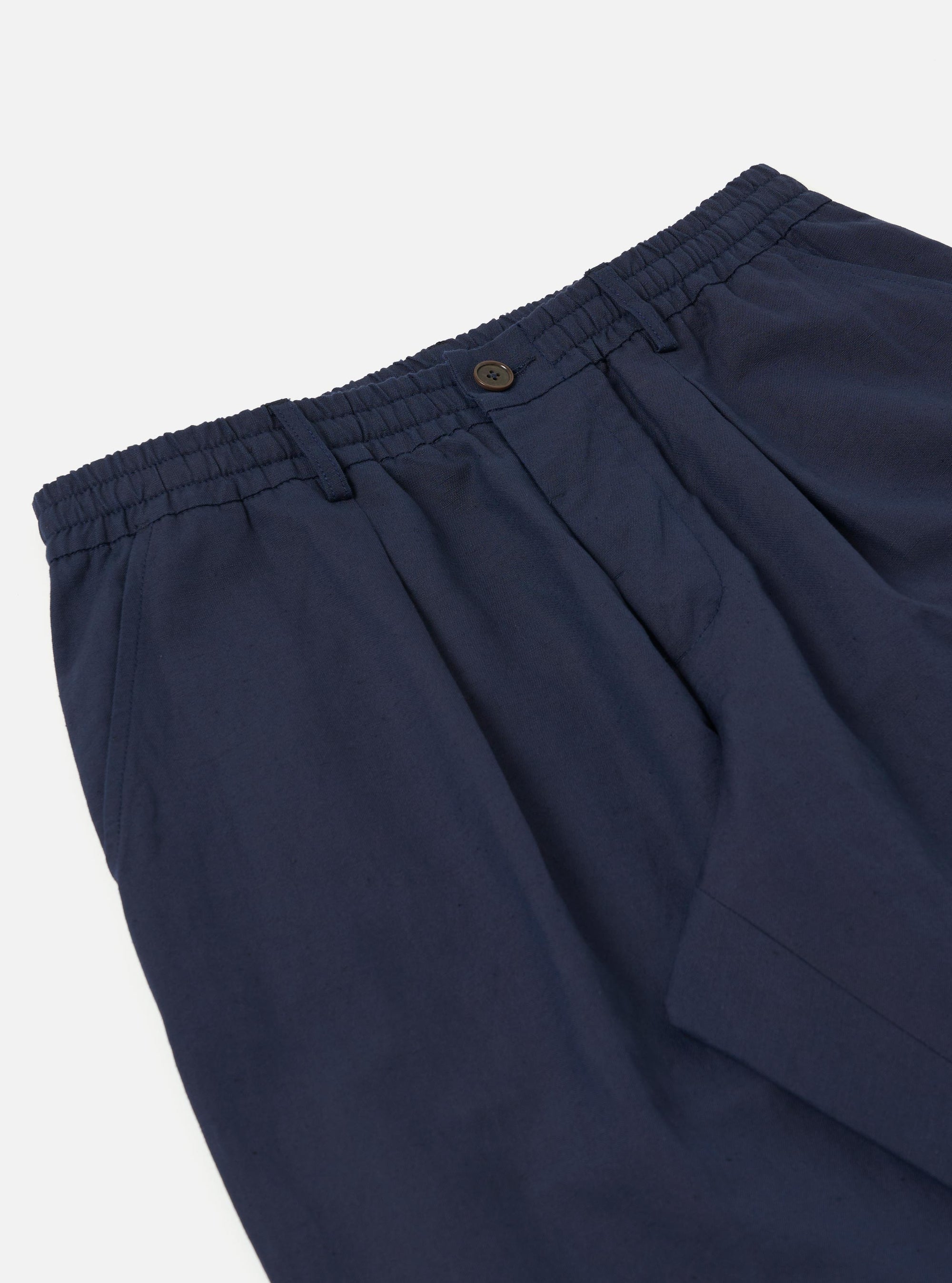 A Navy Linen Slub Weave Oxford Pant is shown from a rear view, laid flat against a plain white background. The image highlights the elasticated waistband with tonal stitching and a single patch pocket on the right side. The dark navy fabric features a distinct, irregular slubbed texture throughout.