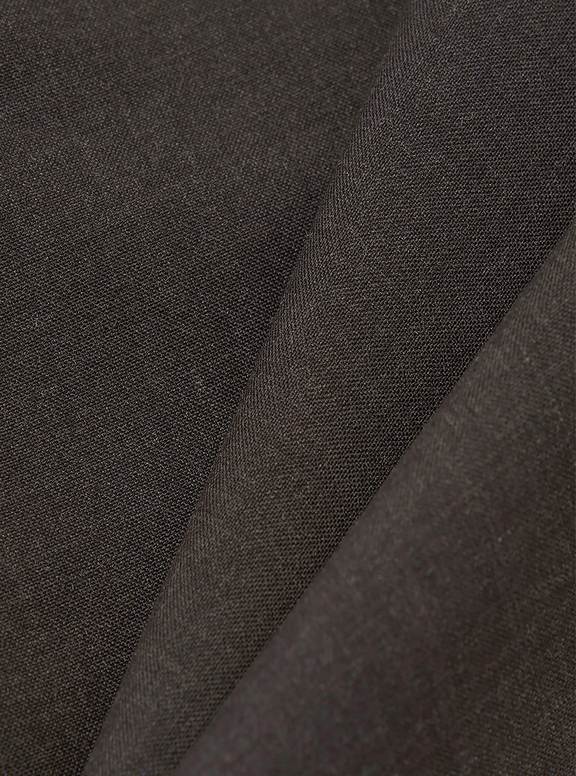 A close-up fabric swatch of the Brown Marl Tropical Suiting Dutch Pant shows a detailed view of the brown marl material. The image highlights the fine, textured weave of the tropical suiting fabric, which consists of a blend of polyester and wool.