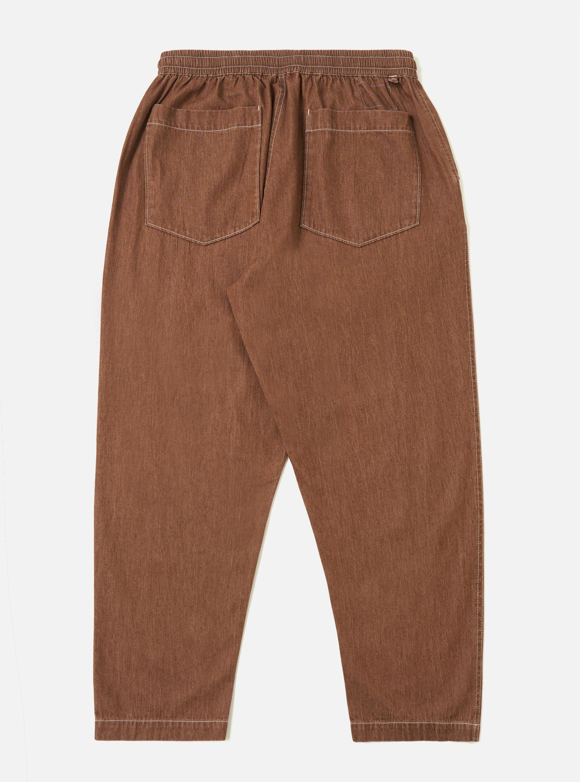 A pair of Brown Meco Denim Hi Water Trousers is shown from the back, laid flat against a solid white background. The image highlights the rear construction, featuring two large patch pockets and a straight-leg silhouette.