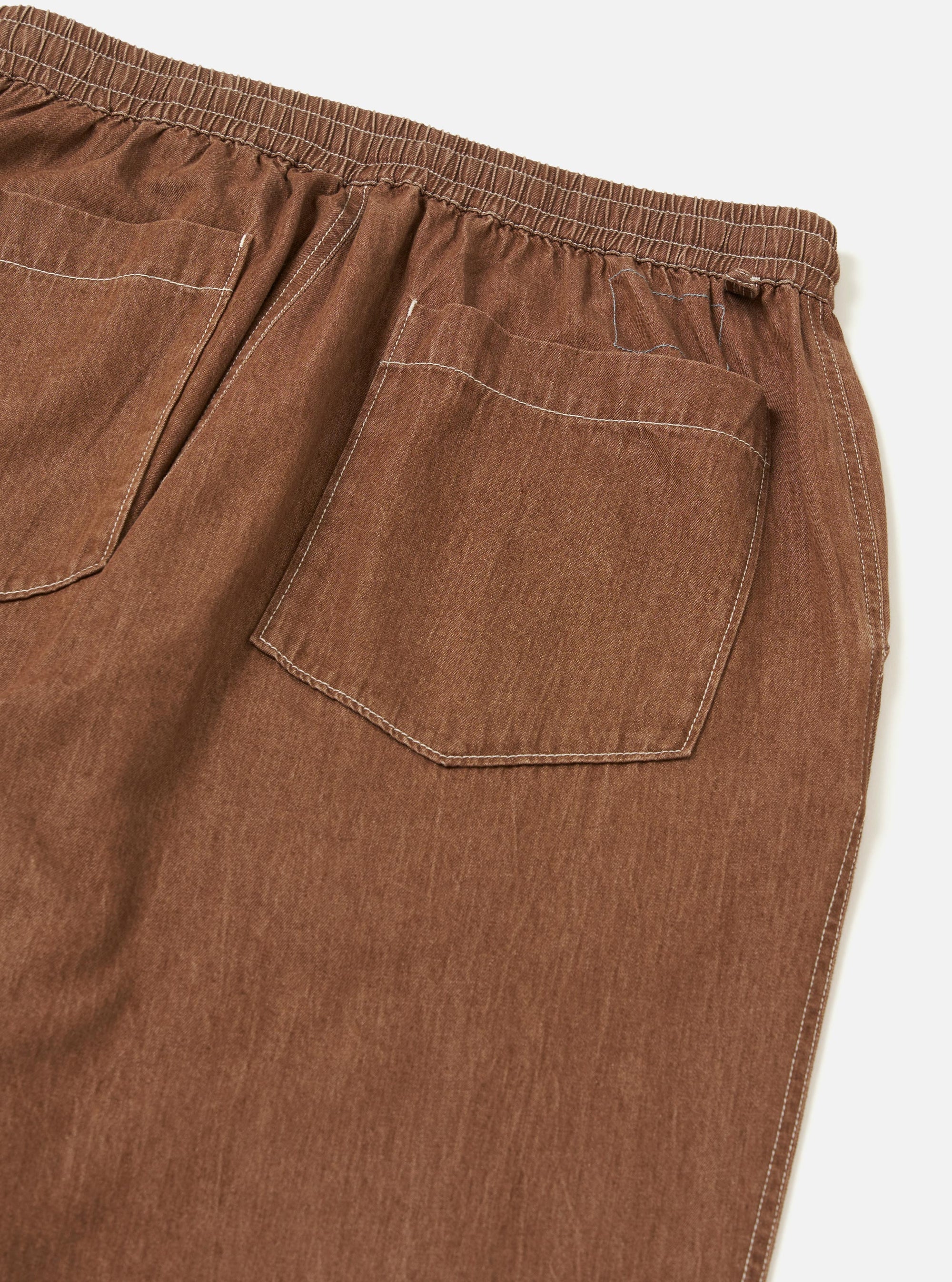 A pair of Brown Meco Denim Hi Water Trousers is displayed from a rear view, showing the back pockets and waistband. The garment is laid flat against a plain white background.
