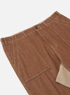 A pair of brown meco denim patched fatigue pants is displayed flat against a plain white background. The trousers feature a straight leg, large patch pockets, and tonal reinforcement patches.