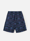 A pair of Navy Madras Patchwork Vacation Shorts is shown laid flat against a solid white background. The shorts feature a vibrant patchwork design with various shades of blue and white in a classic madras plaid pattern. Key details include an elasticated waistband with a drawstring and a relaxed, wide-leg cut.
