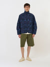 The Navy Madras Patchwork Duty Jacket is displayed flat against a plain white background. The jacket features a boxy, cropped fit and is constructed from a textured patchwork of various navy and blue plaid patterns. Prominent details include a classic pointed collar, a full button-down front, two large lower patch pockets, and a single chest pocket.