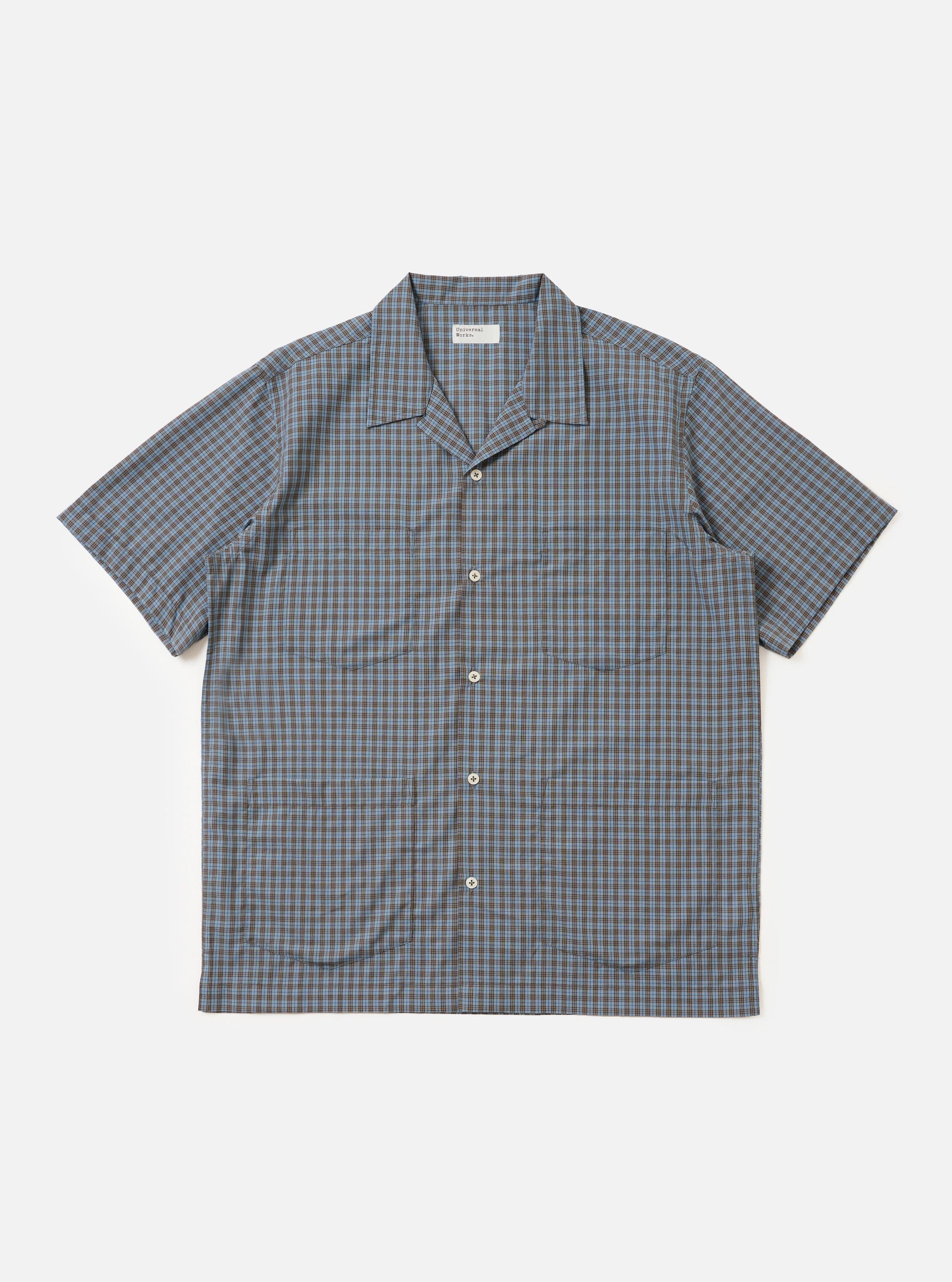 A Pale Blue Check Plaid Summer Overshirt is shown laid flat against a solid white background. The garment features a light blue and white plaid pattern, a classic pointed collar, a full button-down front, and two large utility chest pockets with buttoned flaps.