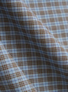 A close-up fabric swatch of the Pale Blue Check Plaid Summer Overshirt is shown, detailing the textured cotton-polyester weave. The pattern consists of a light blue and white checked design with thin orange and navy lines creating a plaid effect. The image focuses solely on the material and its intricate texture.