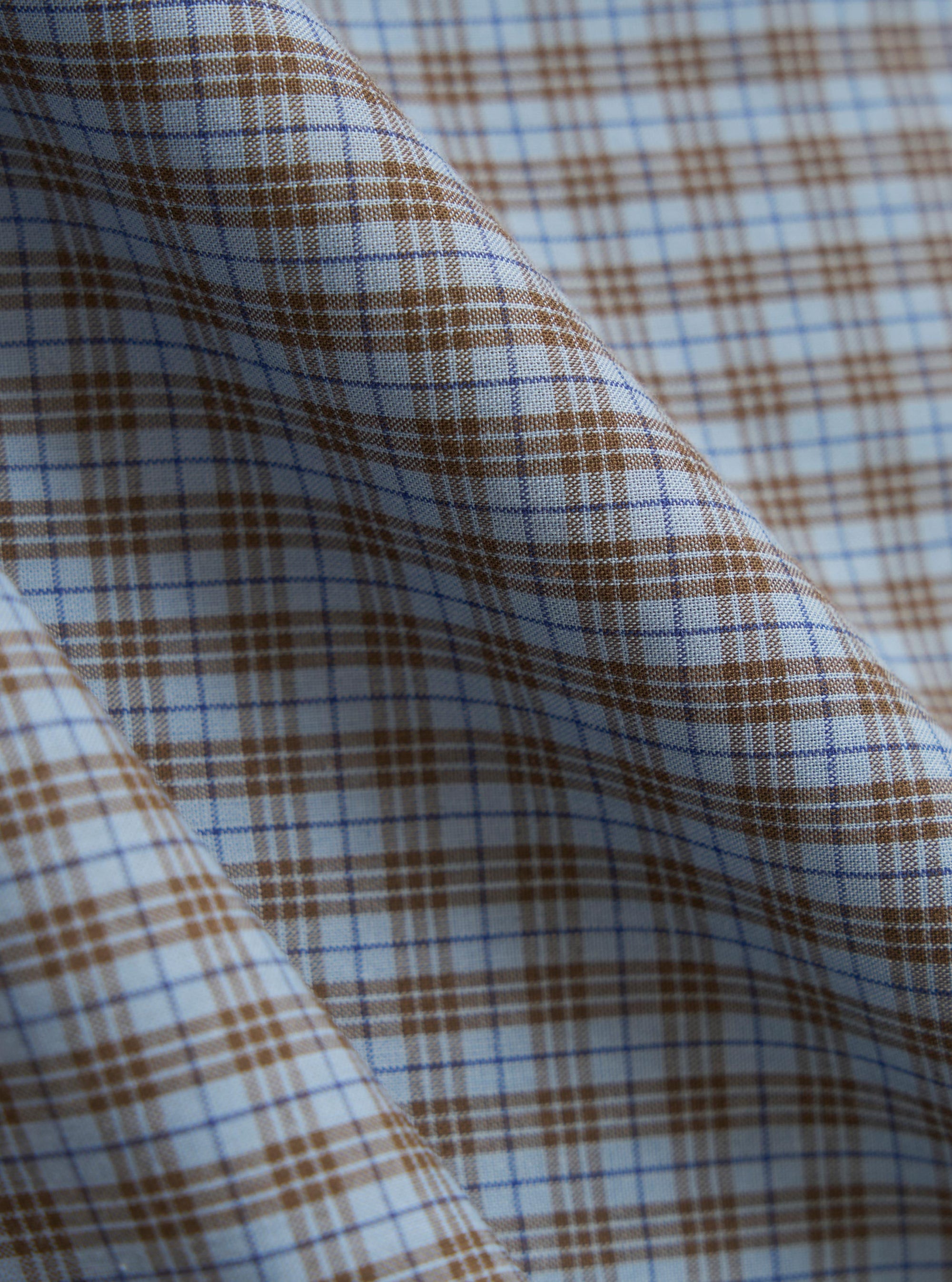 A close-up fabric swatch of the Pale Blue Check Plaid Summer Overshirt is shown, detailing the textured cotton-polyester weave. The pattern consists of a light blue and white checked design with thin orange and navy lines creating a plaid effect. The image focuses solely on the material and its intricate texture.