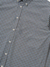 A detail shot of the Pale Blue Check Plaid Lazy Day Shirt is displayed against a plain white background. The image focuses on the chest pocket and button-down front, highlighting the pale blue and white check pattern of the fabric.