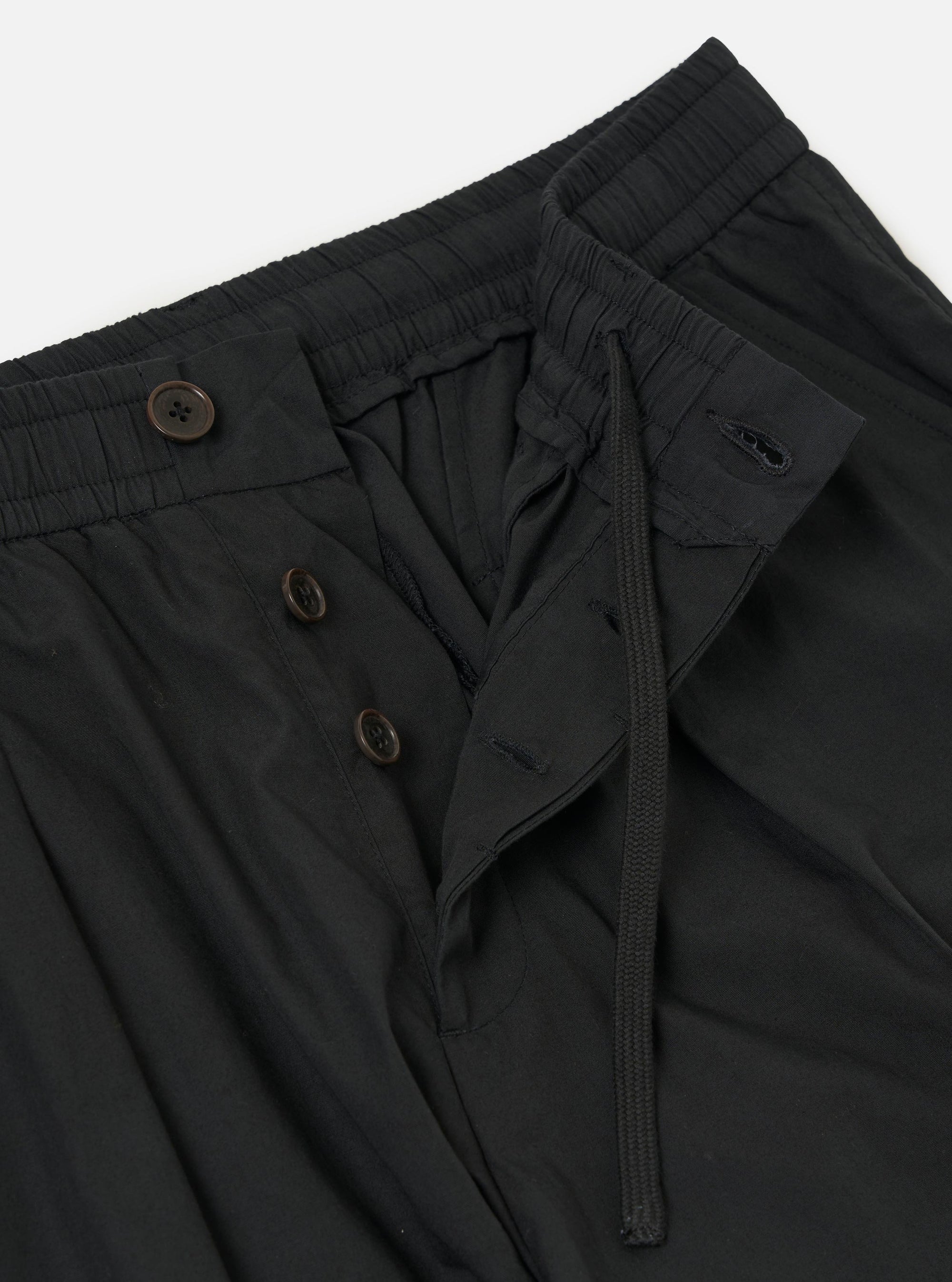 A pair of Black Broadcloth Oxford Pants is displayed from a rear view, laid flat against a solid white background. The trousers feature a wide-leg silhouette, an elasticated waistband with an internal drawstring, and a single rear buttoned flap pocket.