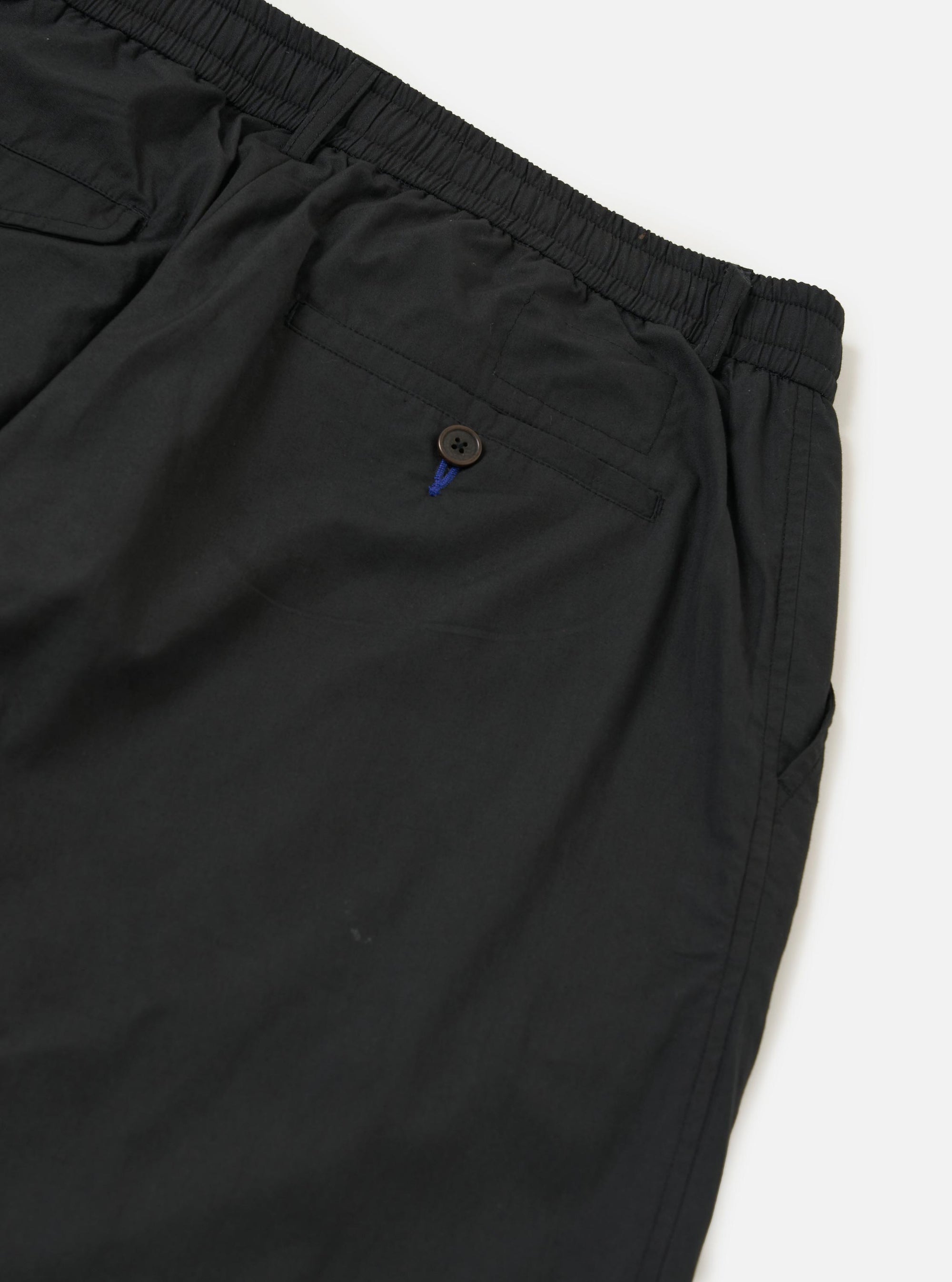 A pair of Black Broadcloth Oxford Pants is shown from the back, laid flat against a plain white background. The image highlights the rear design, featuring two buttoned flap pockets and a central belt loop.