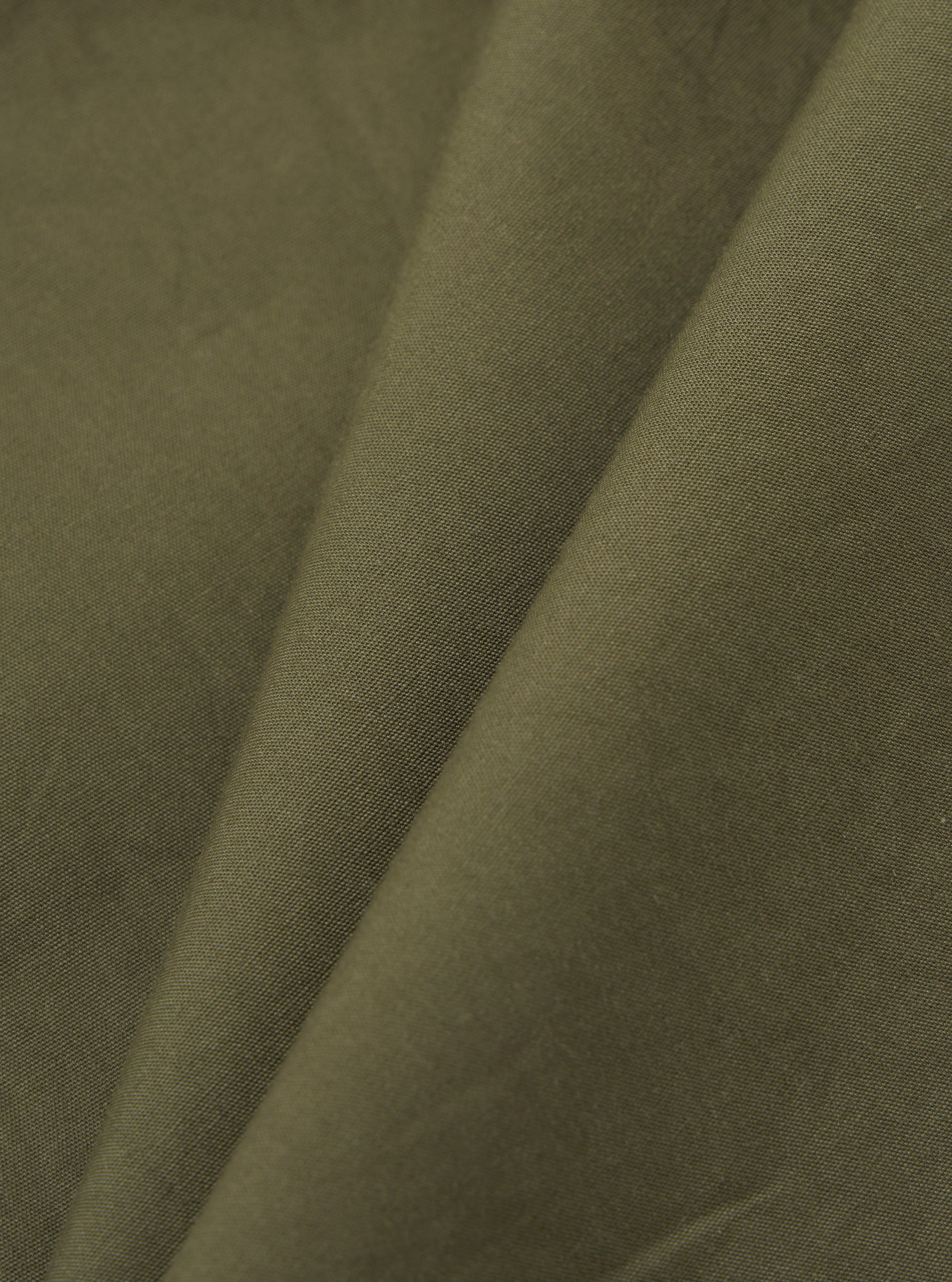 A detailed, close-up fabric swatch of the olive green broadcloth material used for the Olive Broadcloth Oxford Pant. The image highlights the fine, uniform plain weave texture of the cotton fabric.