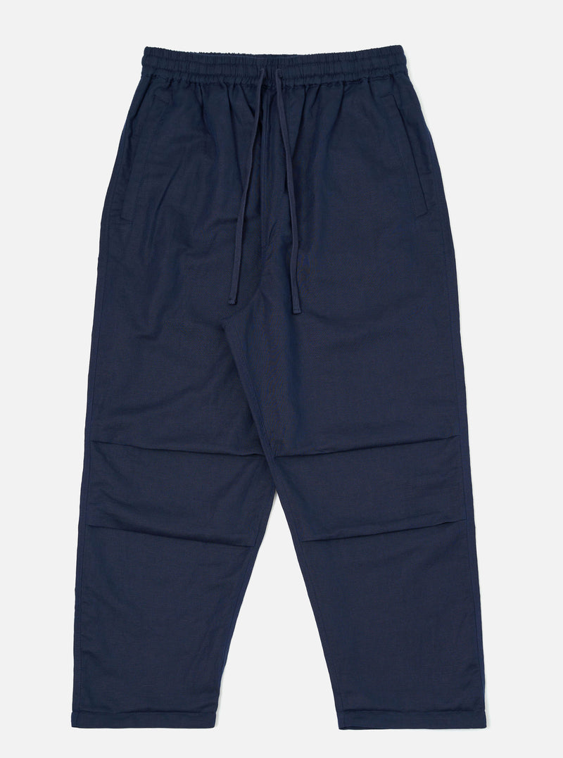 A pair of Navy Linen Cotton Shirting Parachute Pants is shown laid flat against a solid white background. The trousers feature a loose, relaxed fit with an elasticated waistband and a visible drawstring. Key details include angled front hand pockets and pronounced darting at the knees to create a structured, curved leg silhouette.