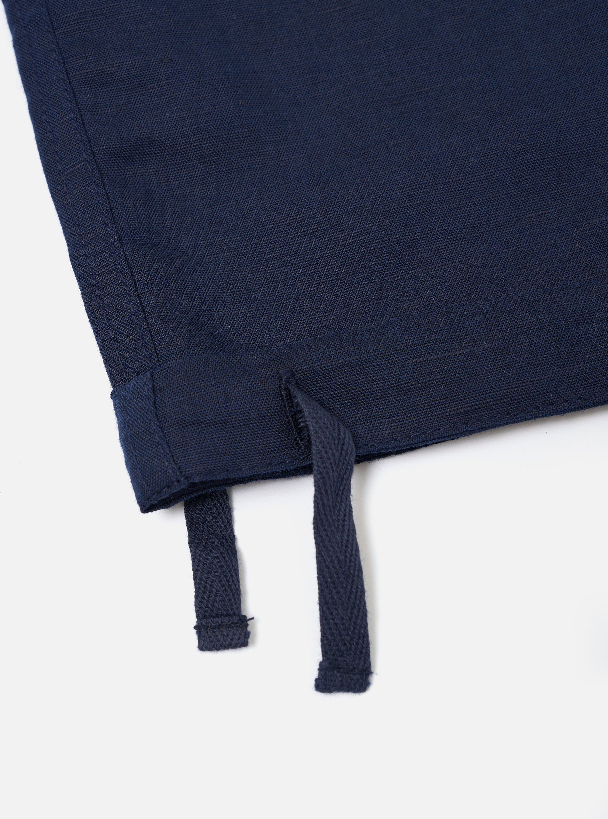 The Navy Linen Cotton Shirting Parachute Pant is shown from a rear perspective, laid flat against a solid white background. The image highlights the two large rear accordion patch pockets with buttoned flaps and the drawstring adjustable hems at the bottom of the wide legs.
