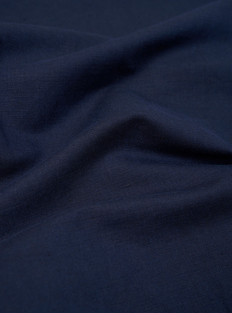 A close-up fabric swatch of the Navy Linen Cotton Shirting Parachute Pant shows a detailed view of the navy blue material. The image highlights the textured weave and the blend of linen and cotton fibers.