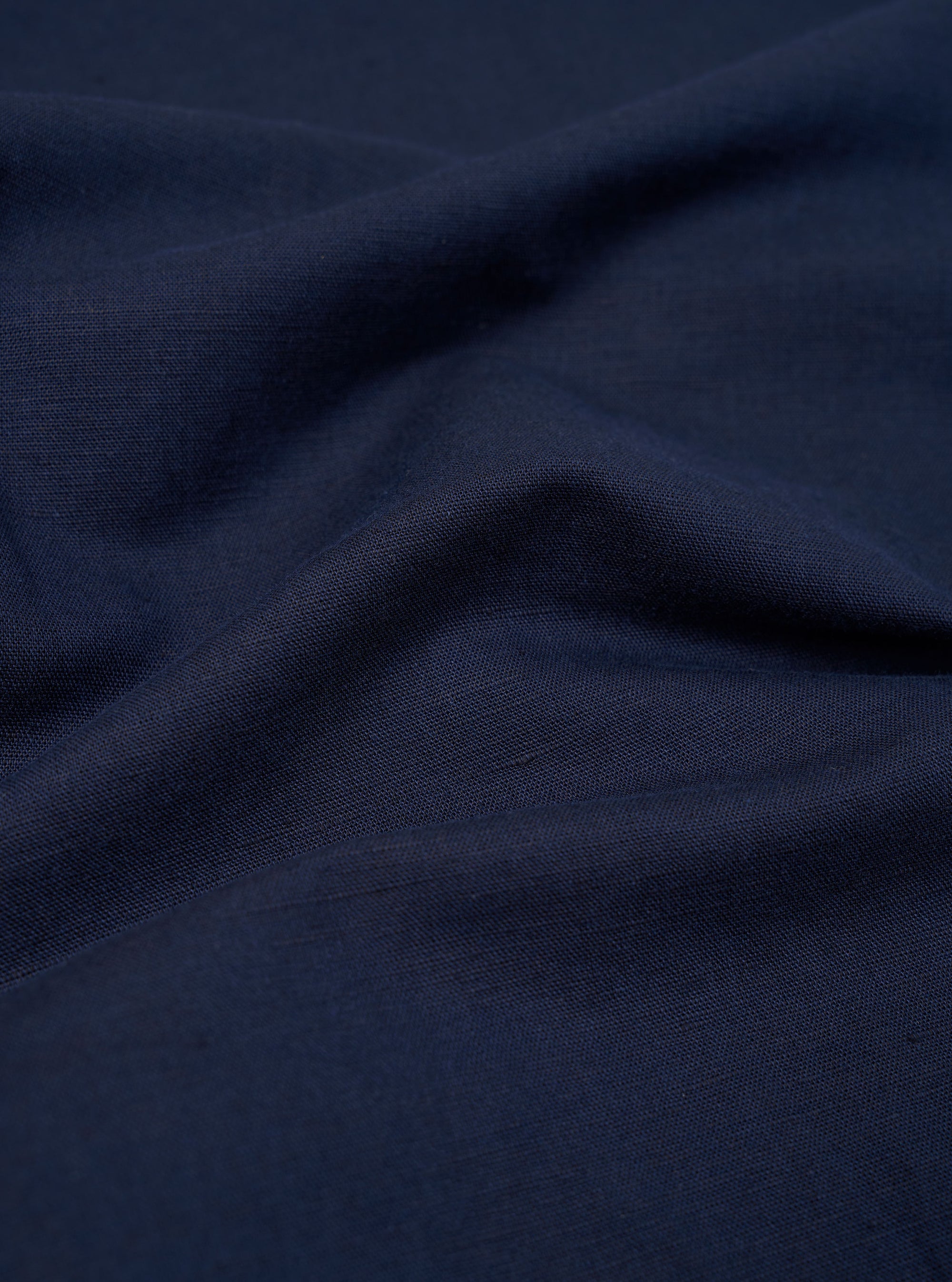 A close-up fabric swatch of the Navy Linen Cotton Shirting Parachute Pant shows a detailed view of the navy blue material. The image highlights the textured weave and the blend of linen and cotton fibers.