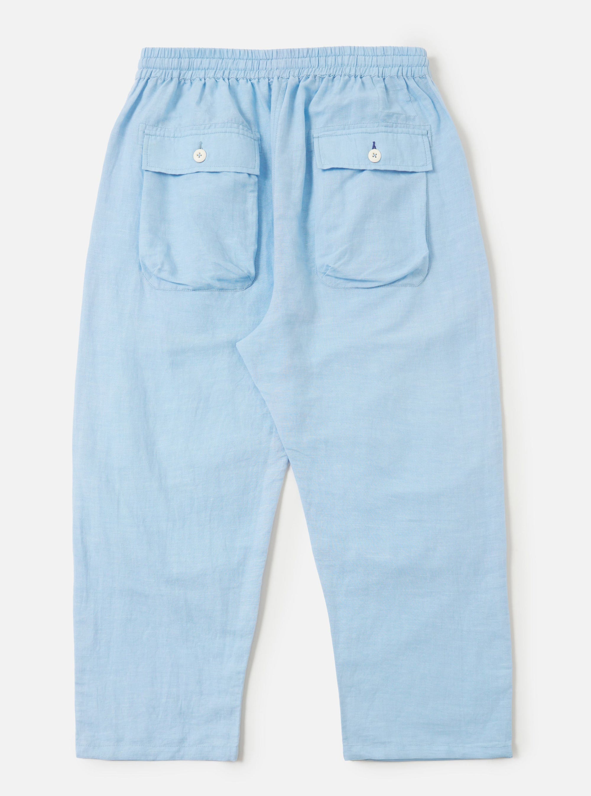A pair of Pale Blue Linen Cotton Shirting Parachute Pants is shown from the back, laid flat against a solid white background. The trousers feature a relaxed, straight-leg silhouette and a visible drawstring at the waistband.