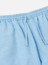 A pair of pale blue linen cotton shirting parachute pants is displayed flat against a plain white background. The garment features a relaxed, straight-leg fit and an elasticated drawstring waistband.
