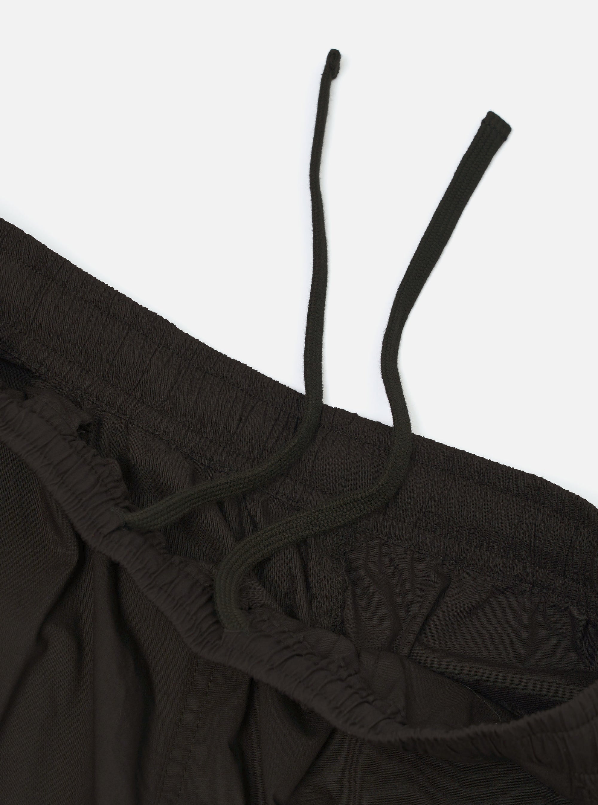 A pair of black broadcloth vacation shorts is displayed flat against a plain white background. The shorts feature a relaxed fit, an elasticated waistband with a visible drawstring, and a smooth, matte fabric texture.