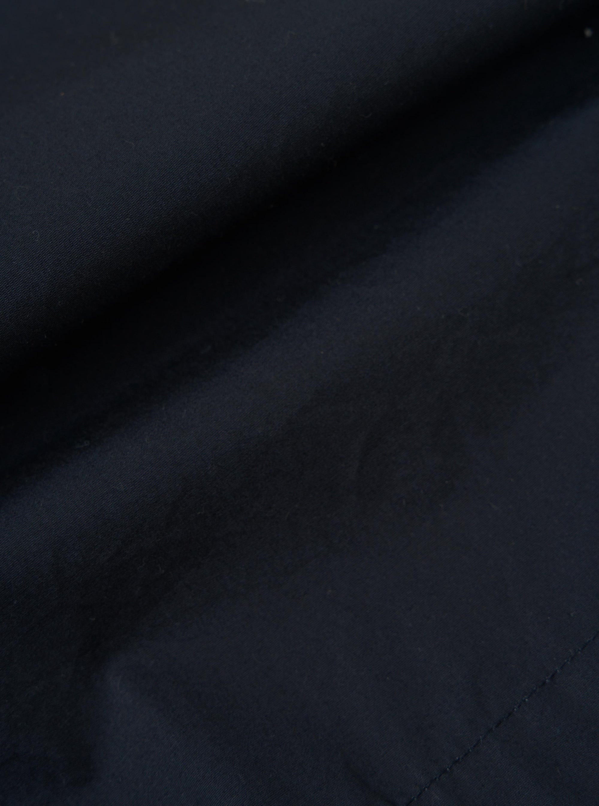 A close-up fabric swatch of the Navy Broadcloth Vacation Short shows the fine, smooth texture of the navy blue cotton material. The image focuses entirely on the fabric weave against a neutral background.