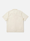 The back of the Ecru Broadcloth Camp Shirt is shown laid flat against a plain white background. The short-sleeve shirt features a back yoke with small pleats for a relaxed fit and an elongated hem with side splits. The crisp, off-white cotton fabric is prominent throughout the garment.