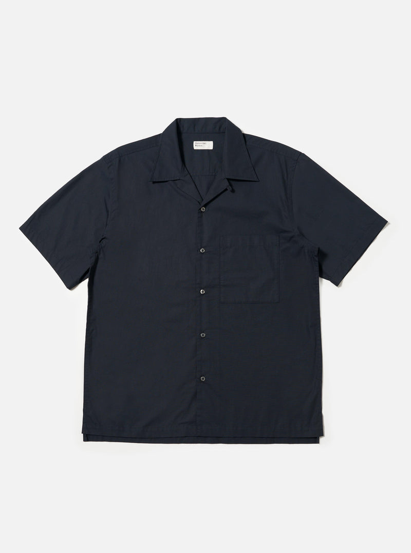 A Navy Broadcloth Camp Shirt is displayed laid flat against a plain white background. The shirt features a dark navy cotton broadcloth fabric, an open camp collar, a full button-down front, and a single large patch pocket on the left chest.
