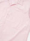 A Pale Pink Broadcloth Camp Shirt is shown from a side-rear perspective, laid flat against a plain white background. The image highlights the short sleeves, a straight hem, and the smooth texture of the pale pink cotton broadcloth.