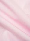 A close-up fabric swatch of the Pale Pink Broadcloth Camp Shirt shows the fine, smooth texture of the 100% cotton material. The image highlights the solid, light pink color and the dense, tight weave of the broadcloth fabric.