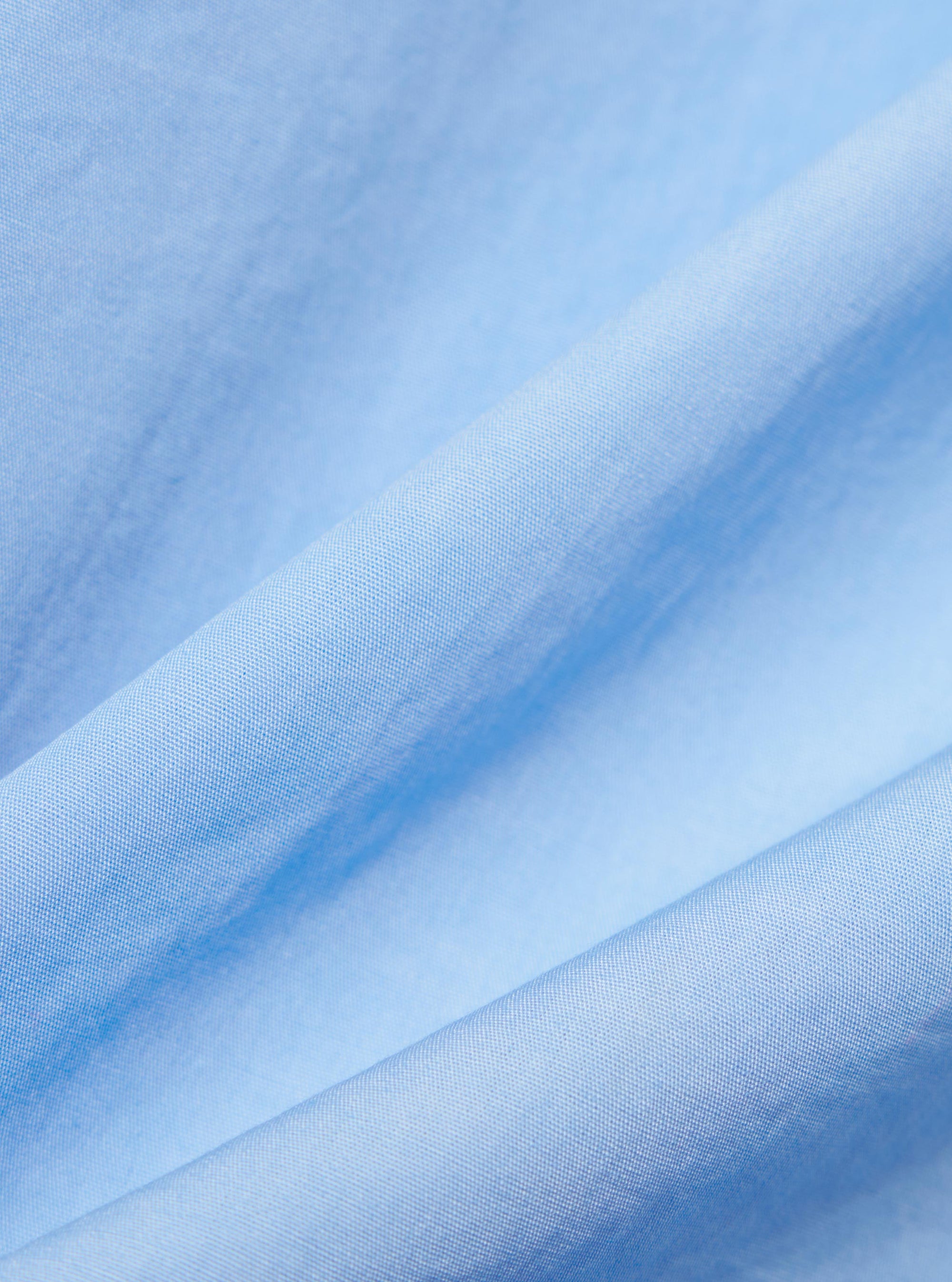 A close-up fabric swatch of the pale blue broadcloth material used for the Pale Blue Broadcloth Camp Shirt. The image highlights the smooth, uniform weave and light blue color of the 100% cotton fabric.