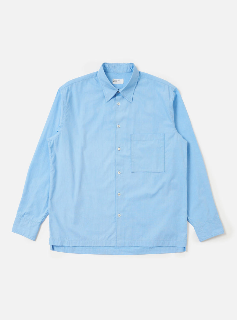 A Pale Blue Broadcloth Lucky Shirt is shown laid flat against a plain white background. The garment features a light blue color, a classic two-piece collar, a full button-down front, and a single large square chest pocket on the left side. The shirt has long sleeves and a straight hem.