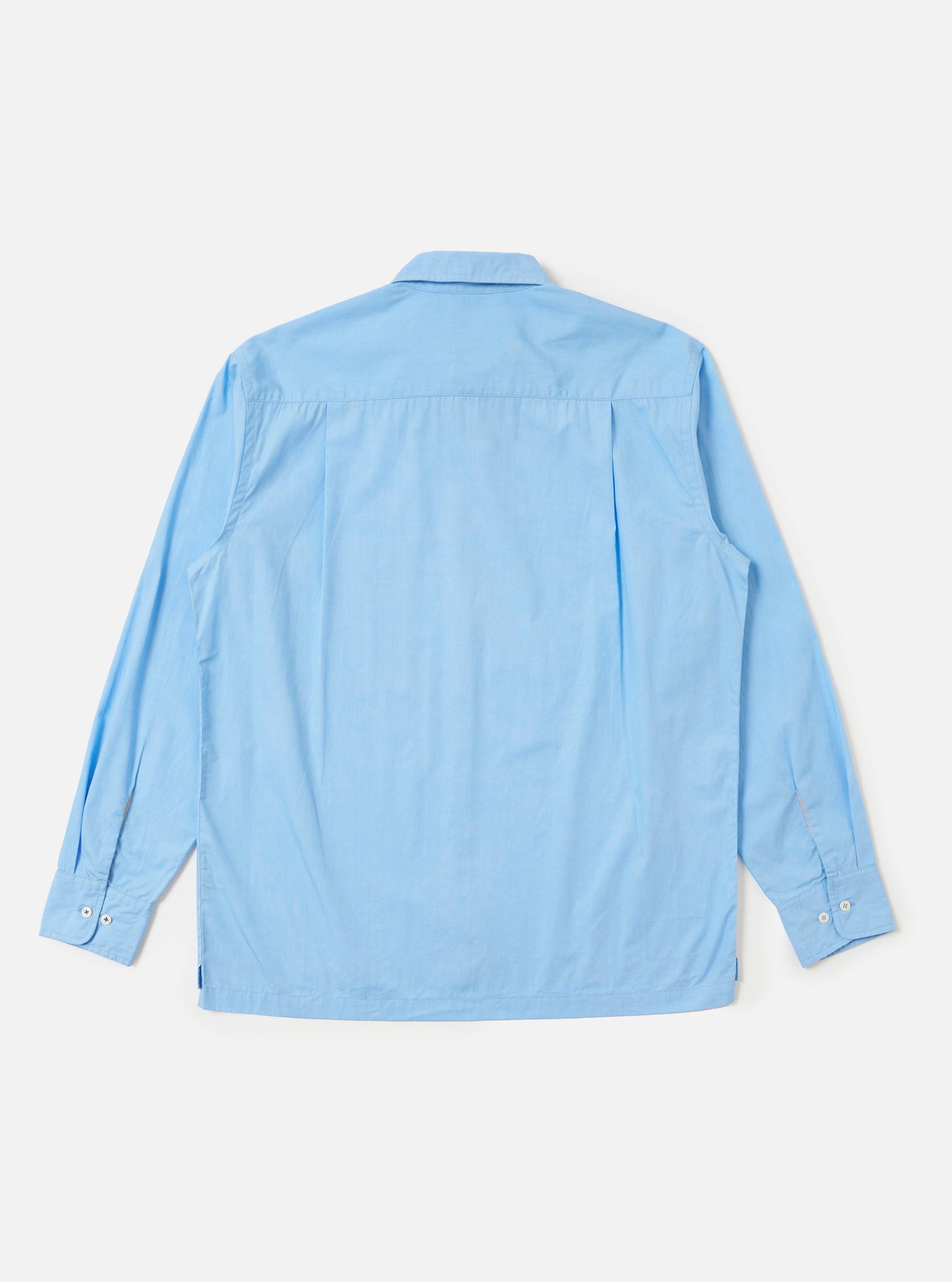 The Pale Blue Broadcloth Lucky Shirt is shown from the back, laid flat against a plain white background. The image highlights the horizontal back yoke and a central box pleat, emphasizing the shirt's relaxed, loose fit.