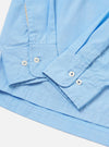 The Pale Blue Broadcloth Lucky Shirt is shown from the back, laid flat against a plain white background. The image highlights the back yoke and a central box pleat designed for a relaxed fit. The lightweight pale blue broadcloth fabric and simple construction are prominent.