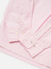 The Pale Pink Broadcloth Lucky Shirt is shown from the back, laid flat against a plain white background. The image highlights the construction of the back yoke and a central box pleat designed for a relaxed fit. The garment is made from a smooth, pale pink cotton broadcloth.