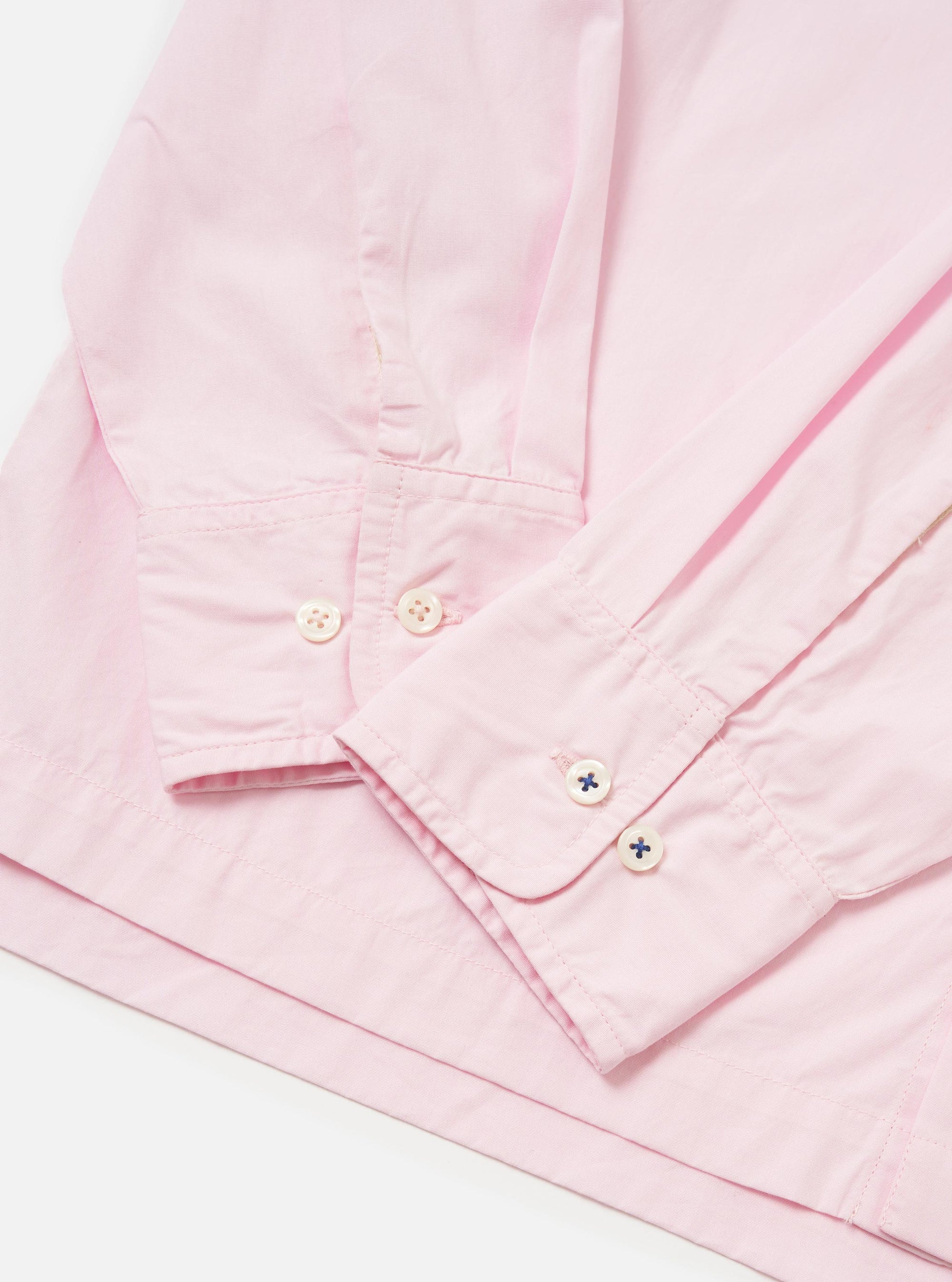 The Pale Pink Broadcloth Lucky Shirt is shown from the back, laid flat against a plain white background. The image highlights the construction of the back yoke and a central box pleat designed for a relaxed fit. The garment is made from a smooth, pale pink cotton broadcloth.