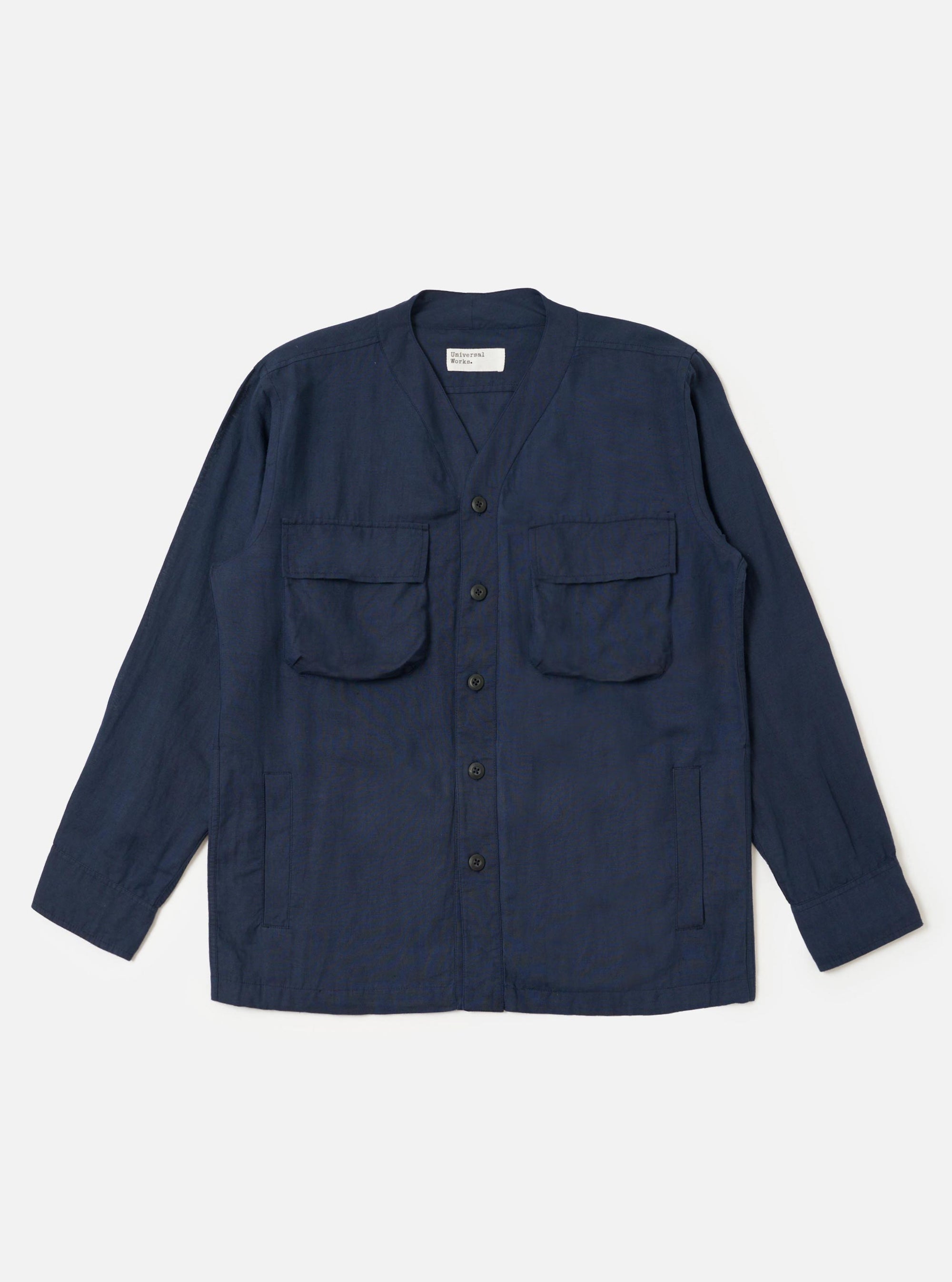 The Navy Linen Cotton Shirting Parachute Shirt is shown laid flat against a solid white background. The garment features a collarless V-neckline with a cardigan-style button front, two large 3D bellows pockets on the chest with buttoned flaps, and two vertical welt hand pockets near the hem. The shirt has long sleeves with adjustable button cuffs and a straight hem with an internal drawcord.