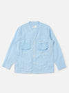 The Pale Blue Linen Cotton Shirting Parachute Shirt is displayed flat against a plain white background. This collarless, V-neck overshirt features a button-down front, two large 3D bellows pockets with buttoned flaps on the chest, and two vertical welt hand pockets near the waist. The garment is shown with long sleeves and a drawcord hem.