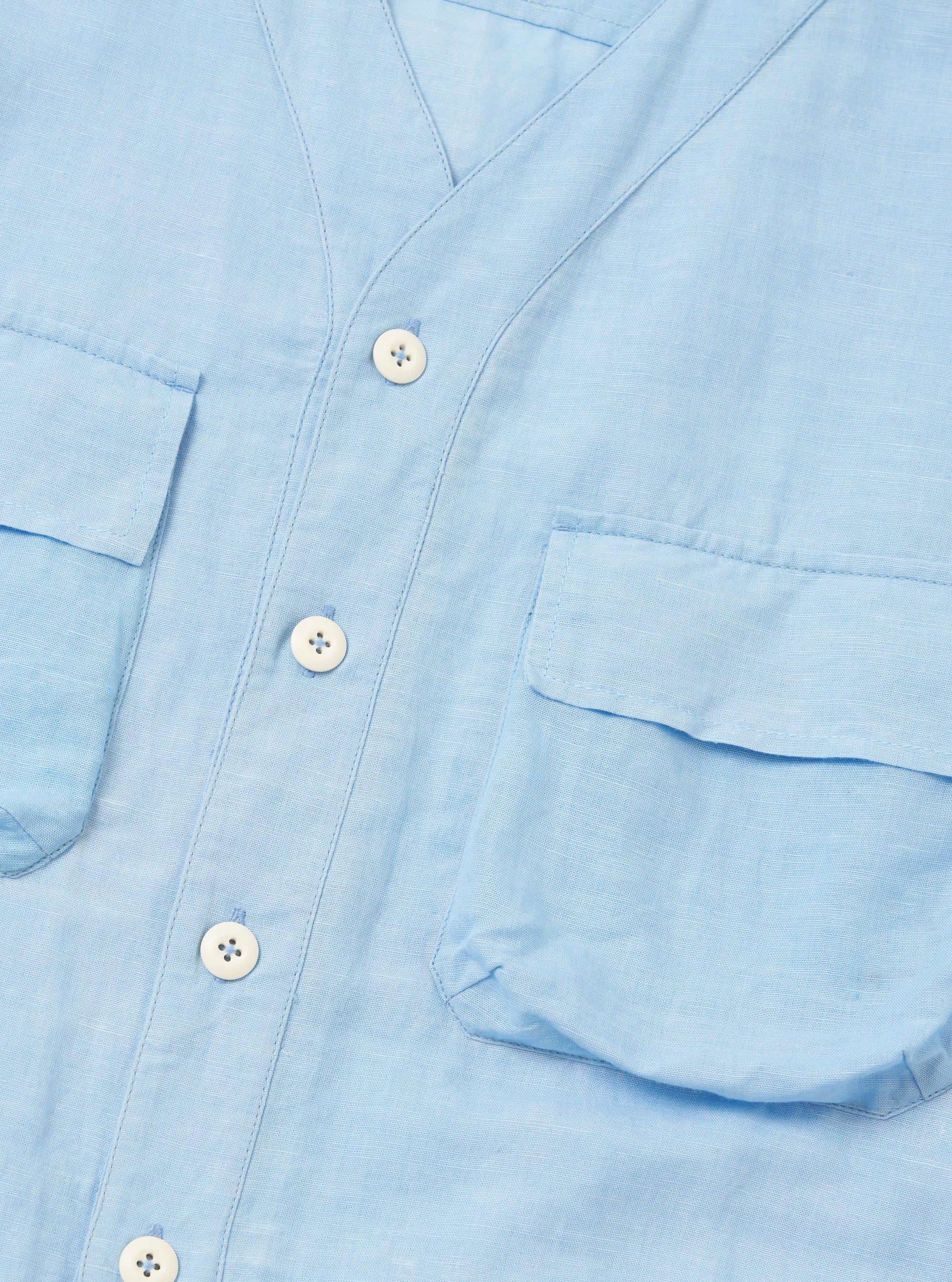 The Pale Blue Linen Cotton Shirting Parachute Shirt is shown from a rear perspective, worn by a model against a plain white background. The image emphasizes the relaxed fit of the overshirt, its light blue color, and the clean stitching along the shoulders and back. The model's hands are placed in the front pockets, highlighting the functional design of the garment.