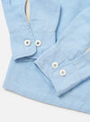 A model is wearing the Pale Blue Linen Cotton Shirting Parachute Shirt, shown from a rear side angle against a plain white background. The shirt features a relaxed fit with long sleeves, a pointed collar, and a straight hem. The light blue fabric has a subtle textured weave. No other items are prominent in the image.