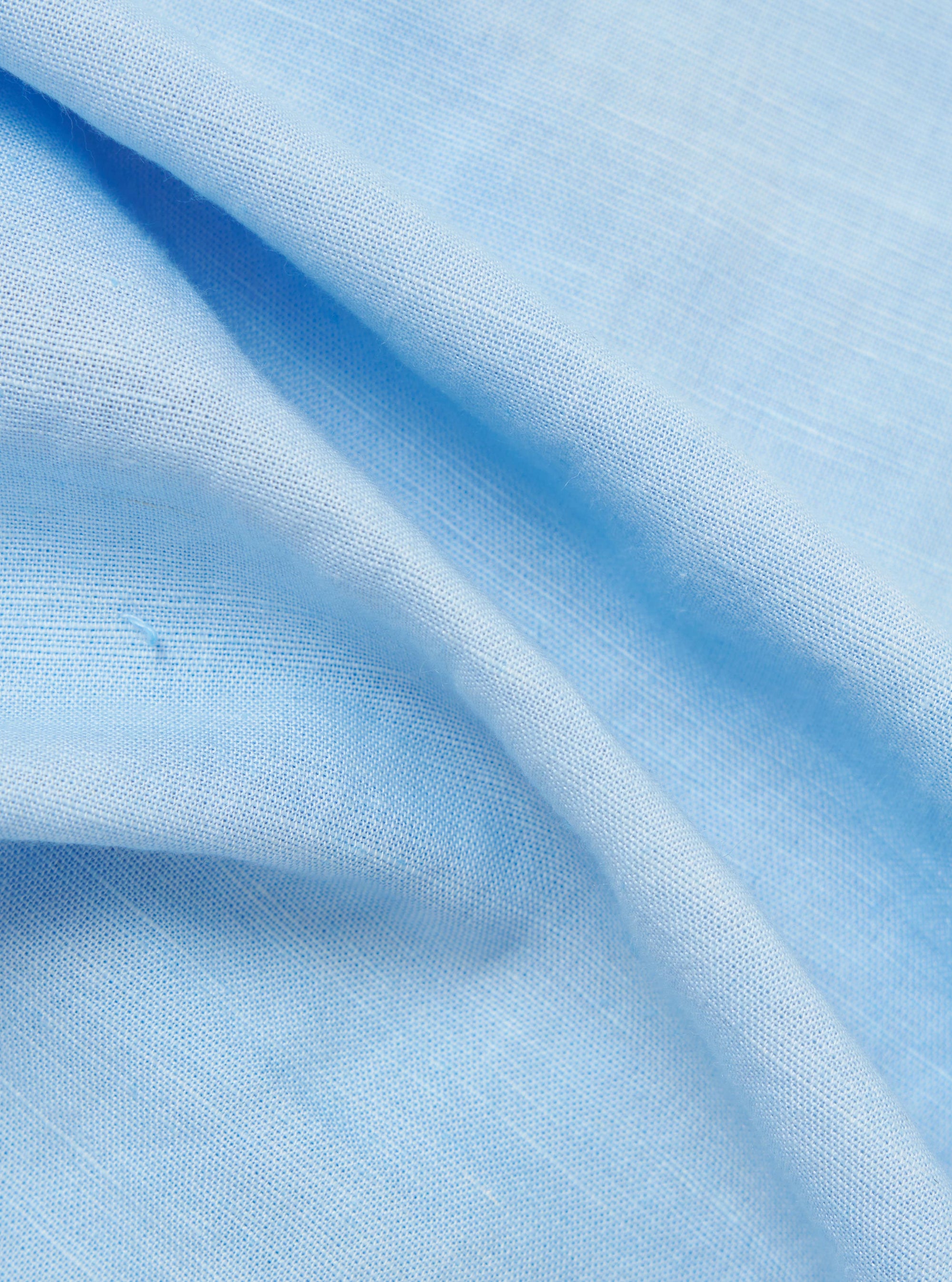 A close-up fabric swatch of the Pale Blue Linen Cotton Shirting Parachute Shirt. The image highlights the fine, textured weave of the material, which features a light blue color with a subtle, natural linen-cotton grain.