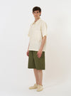 The Ecru Broadcloth Ewan Shirt is shown laid flat against a solid white background. The shirt is a short-sleeved, pullover style featuring a quarter-zip neckline with a silver-toned zipper. It has a classic pointed collar, a single patch pocket on the left chest, and a straight hem with small side splits.