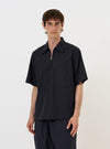 A model is wearing the Navy Broadcloth Ewan Shirt against a plain white background. The shirt is a navy blue pullover style featuring a partial zip front, a classic collar, and a single chest pocket. The model is shown from the waist up, and the garment is worn untucked. No mannequin is present in the image.