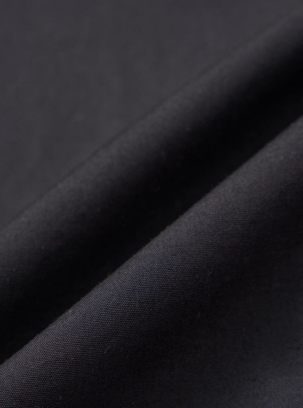 A close-up fabric swatch of the black broadcloth used for the Black Broadcloth Ewan Shirt. The image highlights the smooth, fine weave and deep black color of the material.