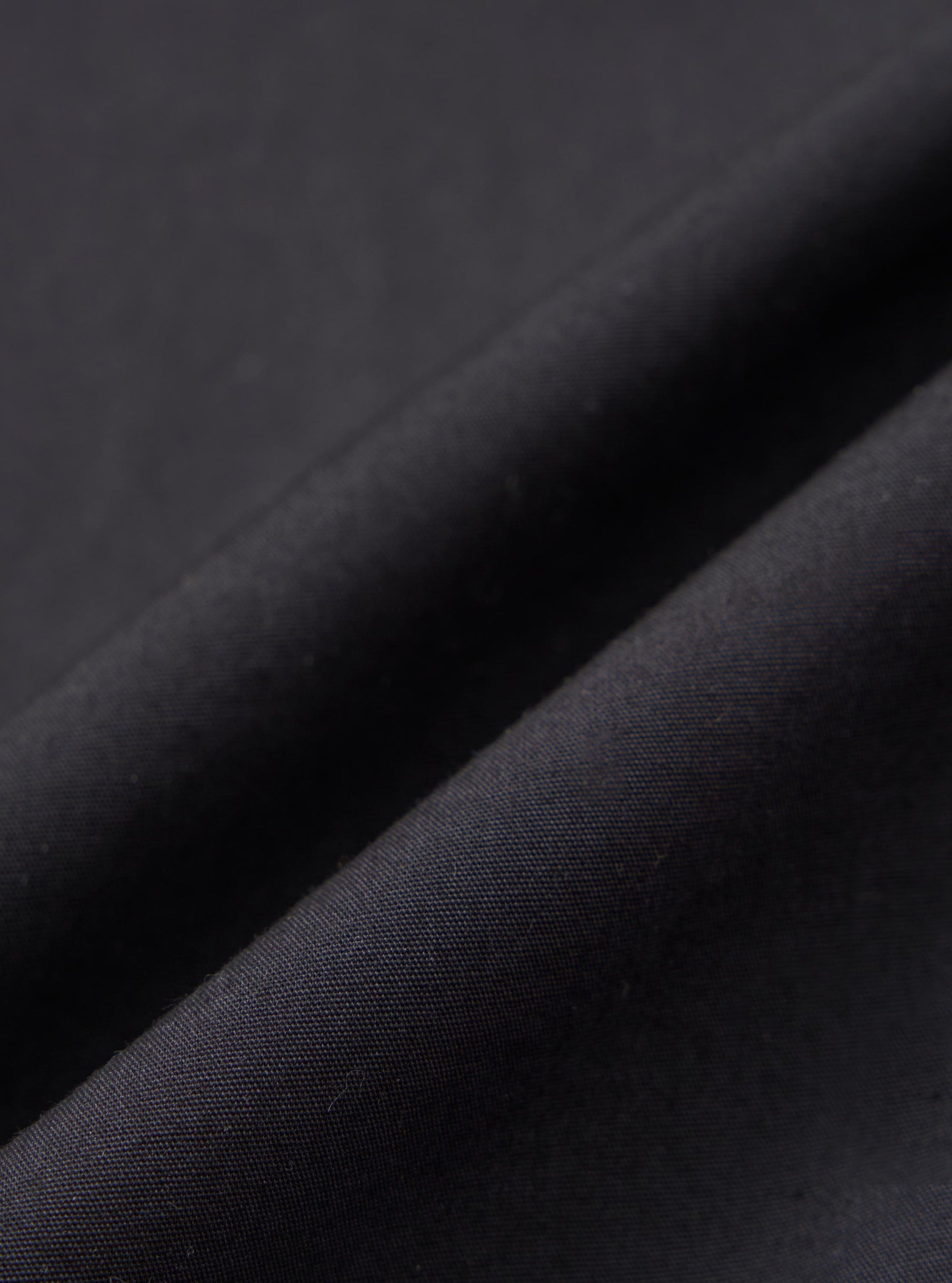 A close-up fabric swatch of the black broadcloth used for the Black Broadcloth Ewan Shirt. The image highlights the smooth, fine weave and deep black color of the material.