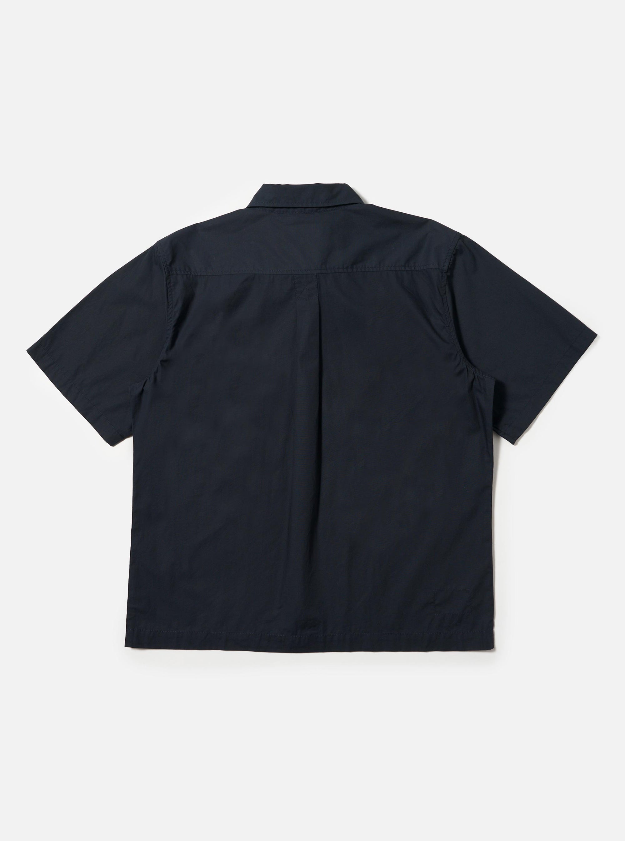 The Navy Broadcloth Ewan Shirt is shown from the back, displayed flat against a plain white background. The image highlights the short sleeves, a straight hem with side splits, and a horizontal yoke with a central box pleat designed for a relaxed fit.
