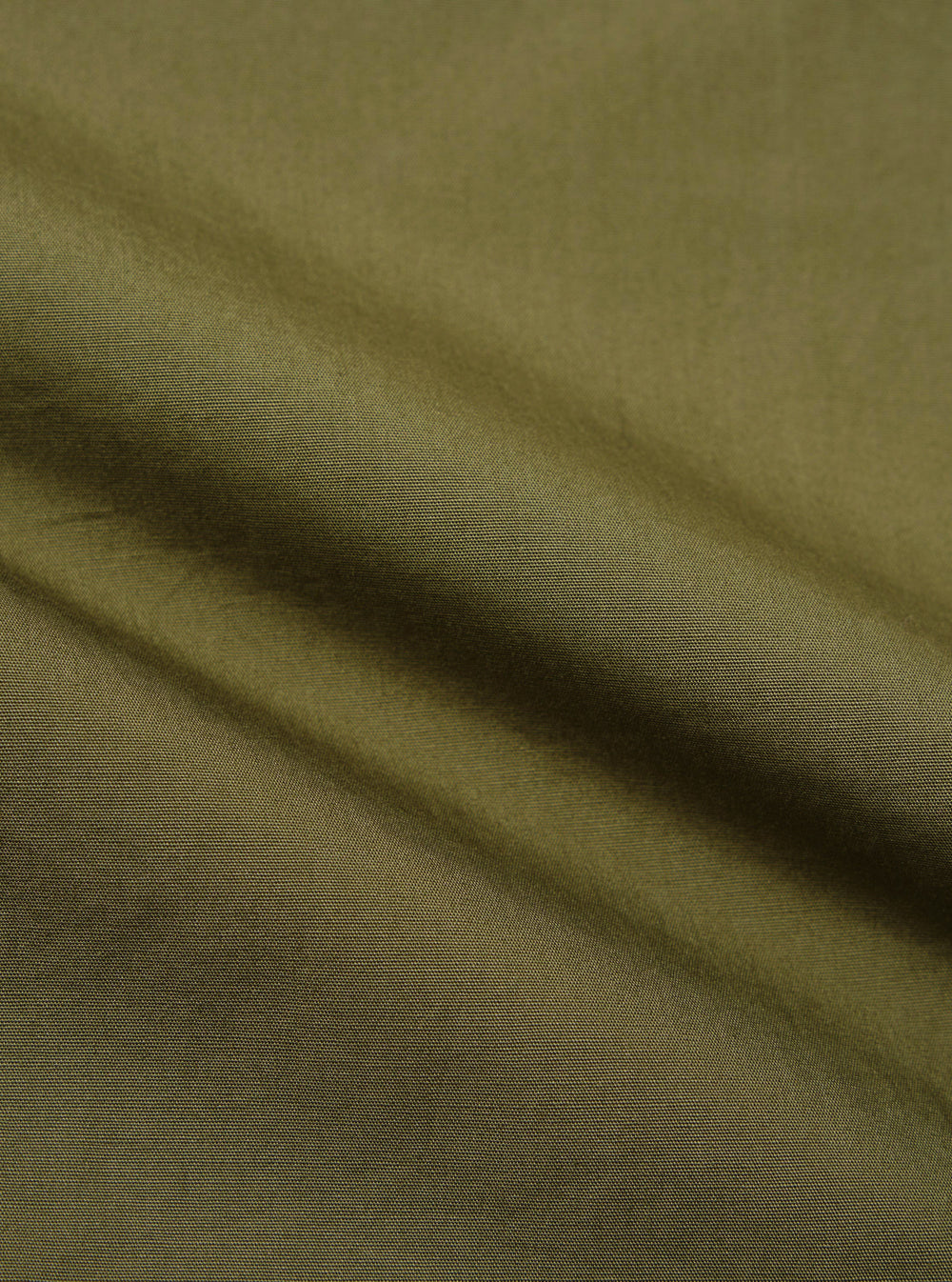 A close-up fabric swatch of the olive green broadcloth used for the Ewan Shirt. The image displays the smooth, tight weave and solid olive color of the material.