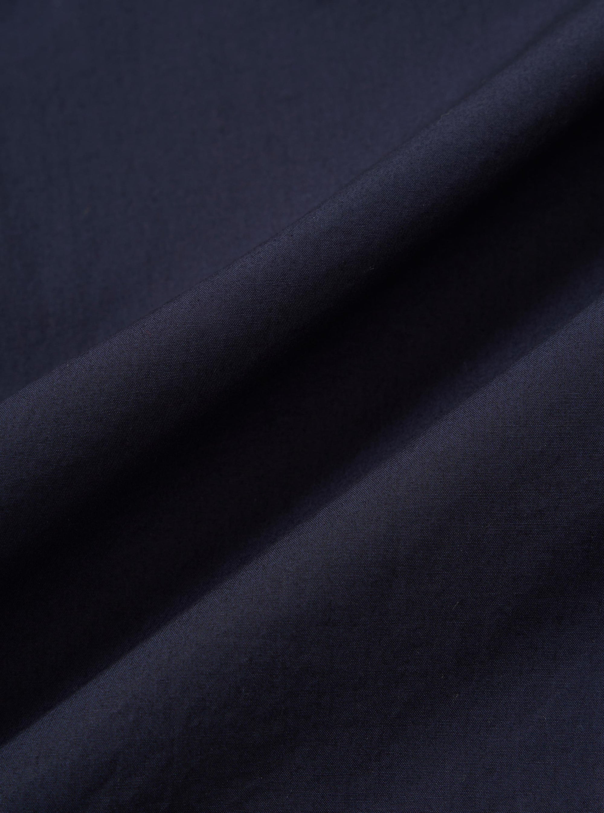 A close-up fabric swatch of the Navy Paper Touch Cotton S/S Fatigue Shirt highlights the smooth, tight weave and deep navy blue color of the material. The image focuses entirely on the texture of the 100% cotton fabric.