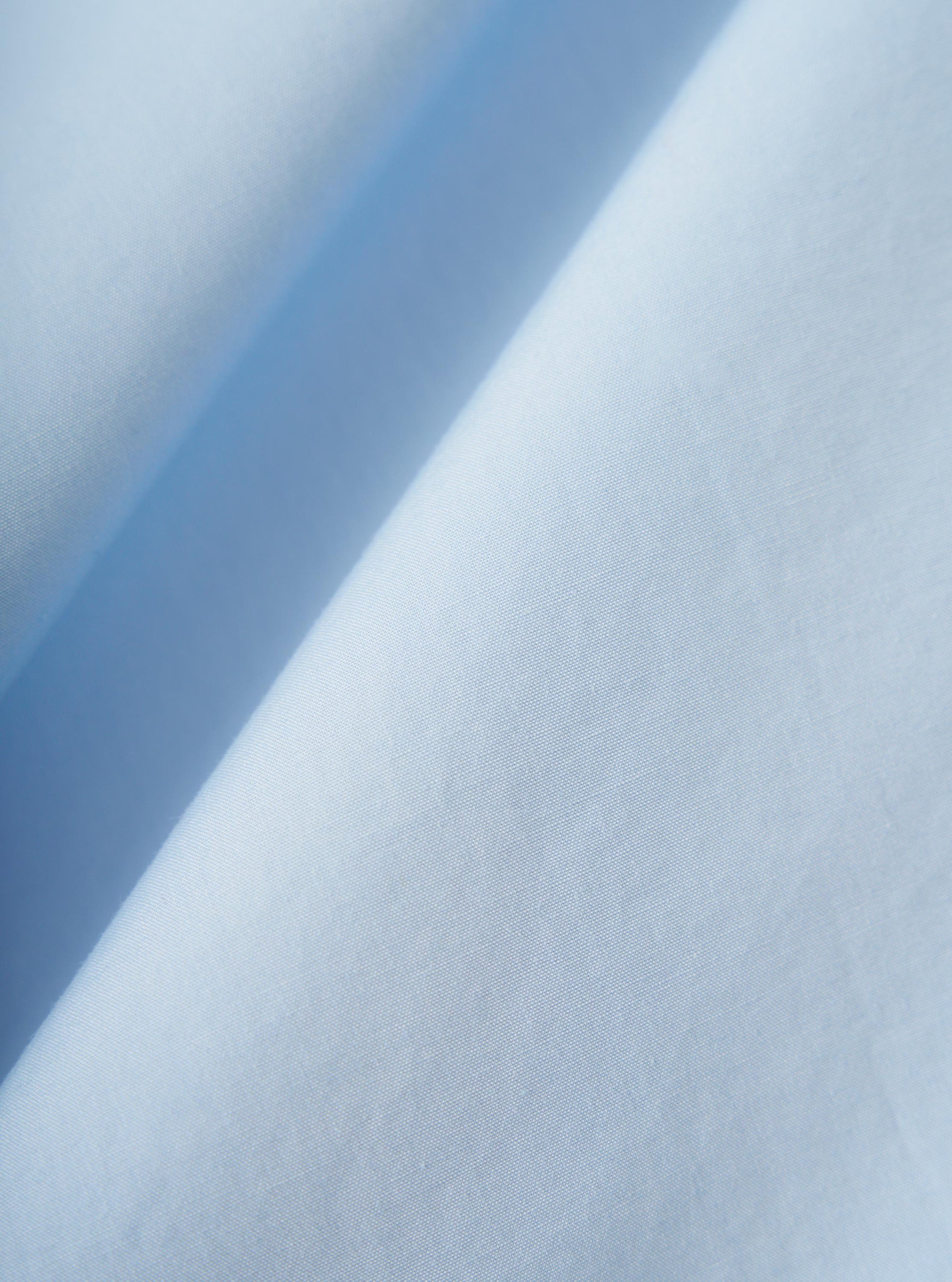 A close-up fabric swatch of the Sky Blue Paper Touch Cotton S/S Fatigue Shirt shows a detailed view of the lightweight, sky blue cotton fabric. The image highlights the material's fine weave and crisp, paper-like texture.