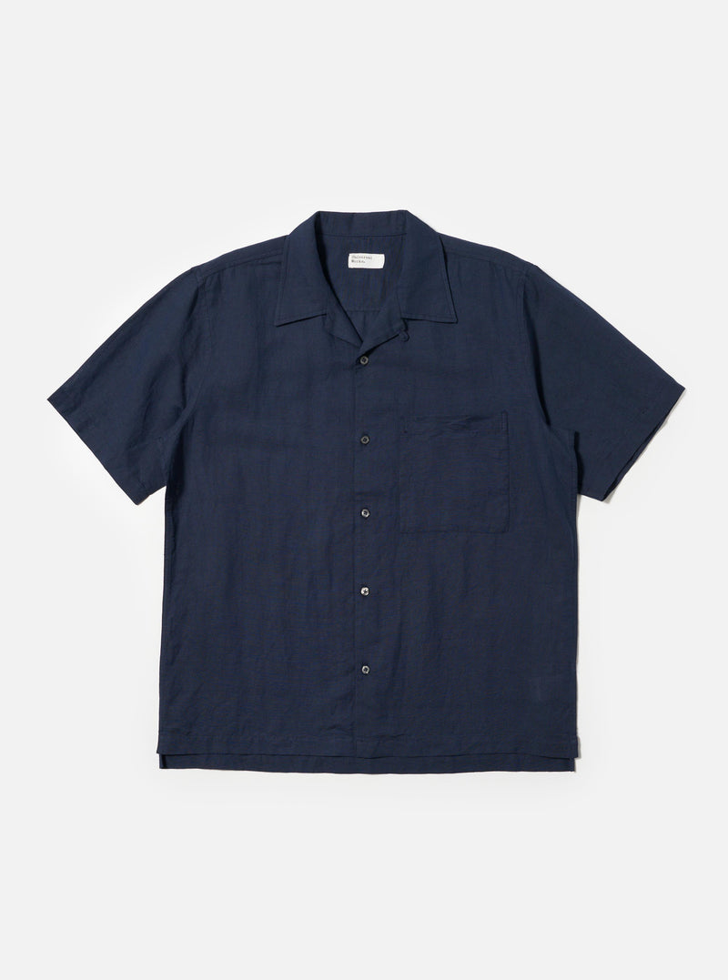 The Navy Linen Cotton Shirting Camp Shirt is displayed flat against a plain white background. This short-sleeve shirt features a camp collar, a single chest pocket on the left side, and a straight hem. The navy blue fabric has a subtle, textured appearance from the linen-cotton blend.